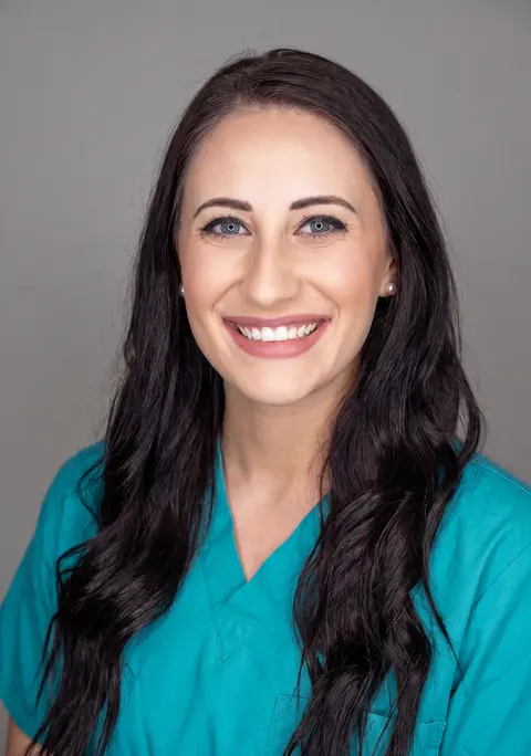 AI example headshot: woman with long dark hair in teal scrubs