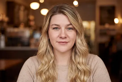 AI example dating photo: young blonde woman in a warm cafe