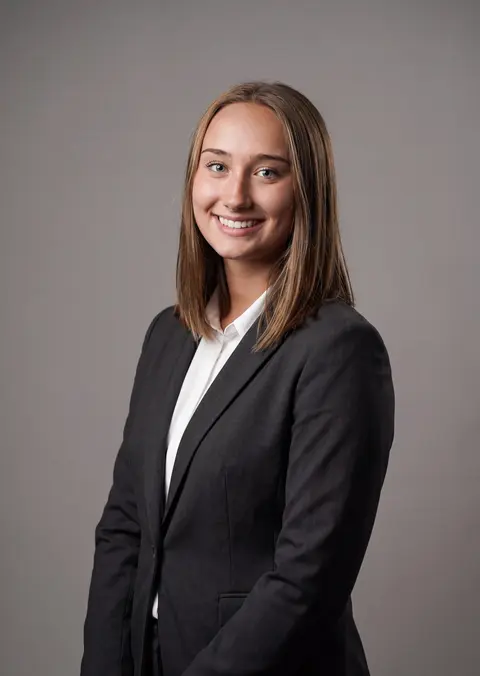 AI example headshot: woman in a black blazer and white shirt on a gray background