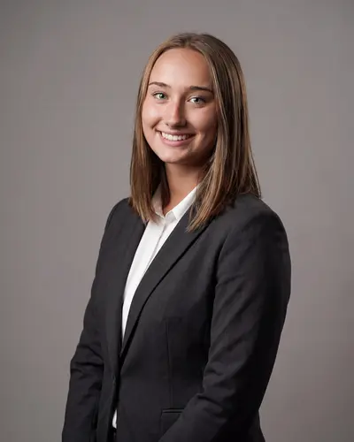 AI example made from that photo: the same woman in a black blazer on a gray background