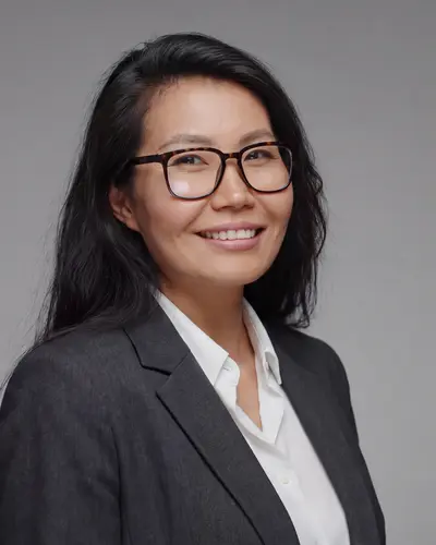 AI example made from that photo: the same woman in a dark blazer on a gray background