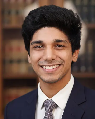 AI example made from that photo: the same man in a navy suit and tie in front of law books